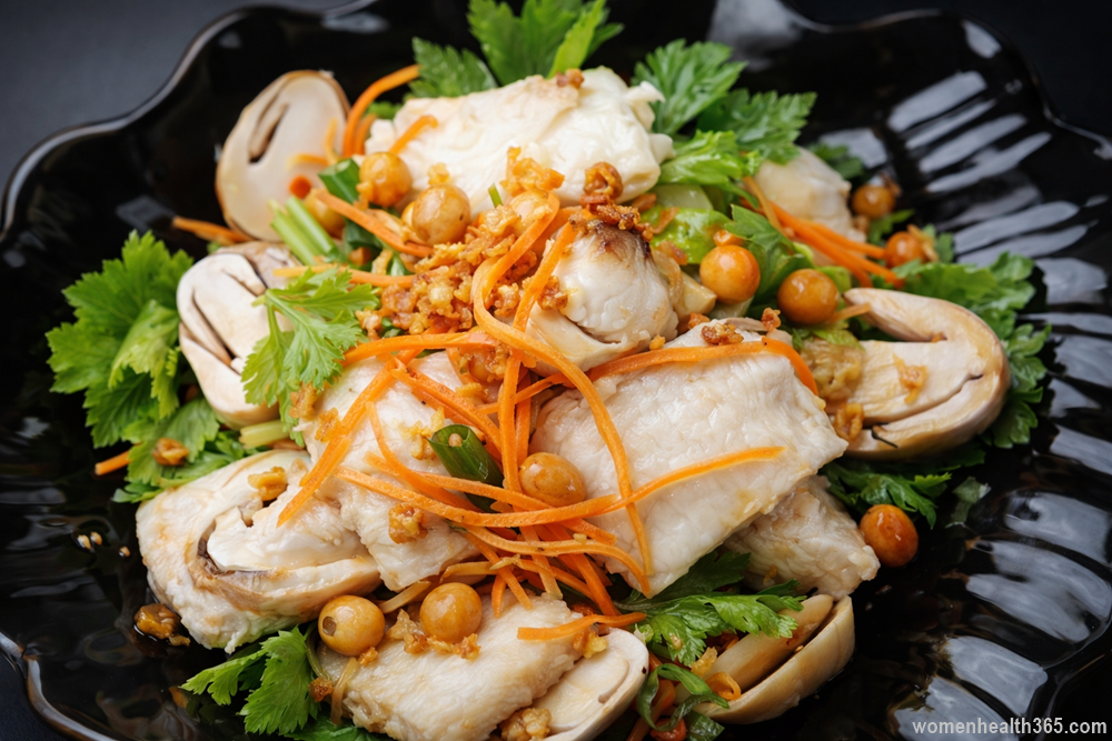 Grouper Salad Thai style served on a black plate with sliced grouper fish, straw mushrooms, shredded carrots, celery, herbs, and fried garlic